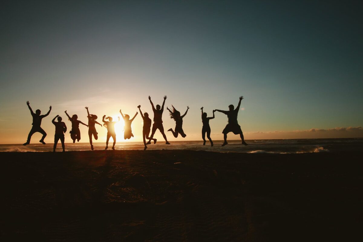 silhouette photography of group of people jumping during golden time